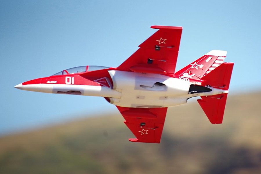 FMS Yak-130 V2 EDF jet model in red and white with '01' marking and star emblem, flying against a blue sky.