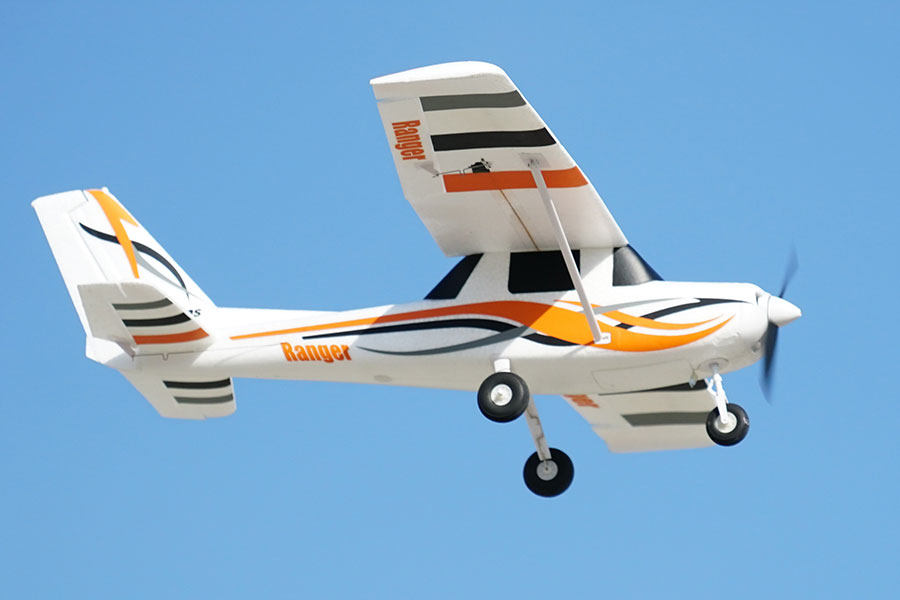 FMS 850mm Ranger RC airplane in flight with orange and black accents, featuring Reflex V3 technology.