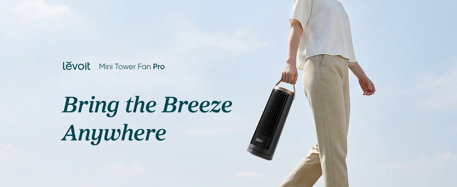 A person walks outdoors holding a sleek, portable tower fan. The sky is clear, emphasizing the fan's mobility and convenience.
