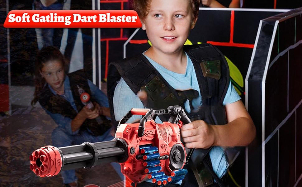 Red and blue toy dart blaster with rotating barrel, held by a child in an indoor play area. Product name 'Soft Gatling Dart Blaster' visible.