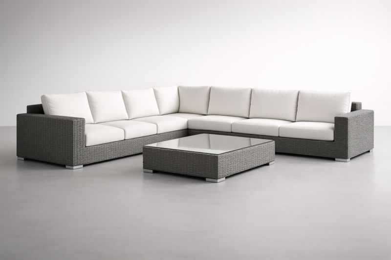 Canapé d'angle modulable en résine tressée avec coussins crème et table basse en verre