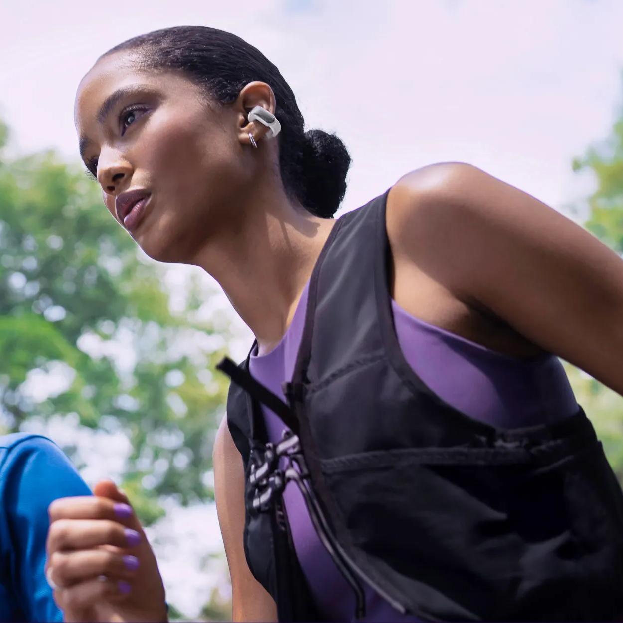 Woman wearing Bose Ultra Open Earbuds while going for a run.