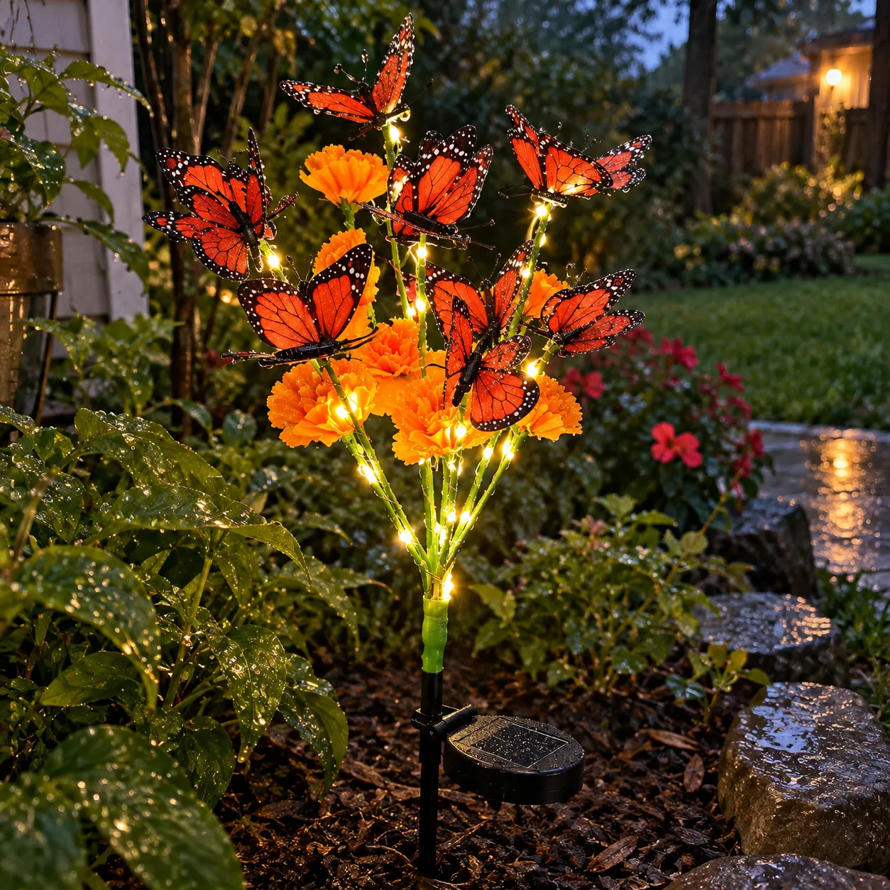 Solarleuchte mit Tagetes und Schmetterling im Gartenbeet nach dem Regen