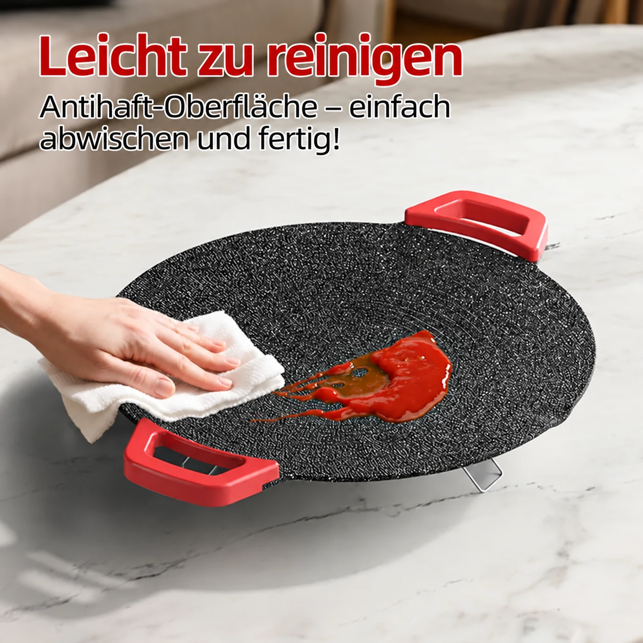 Hand wischt die schwarze gesprenkelte Kochfläche ab
