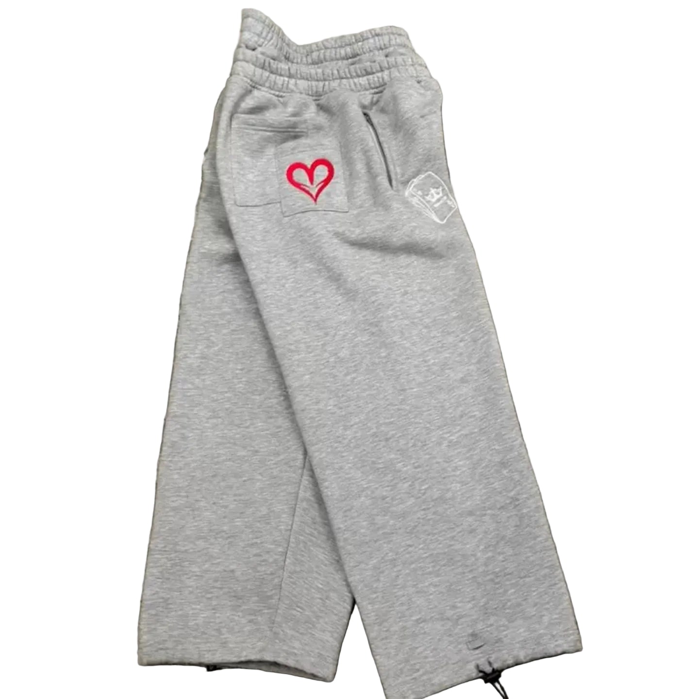 Gray sweatpants with a red heart design on a concrete surface
