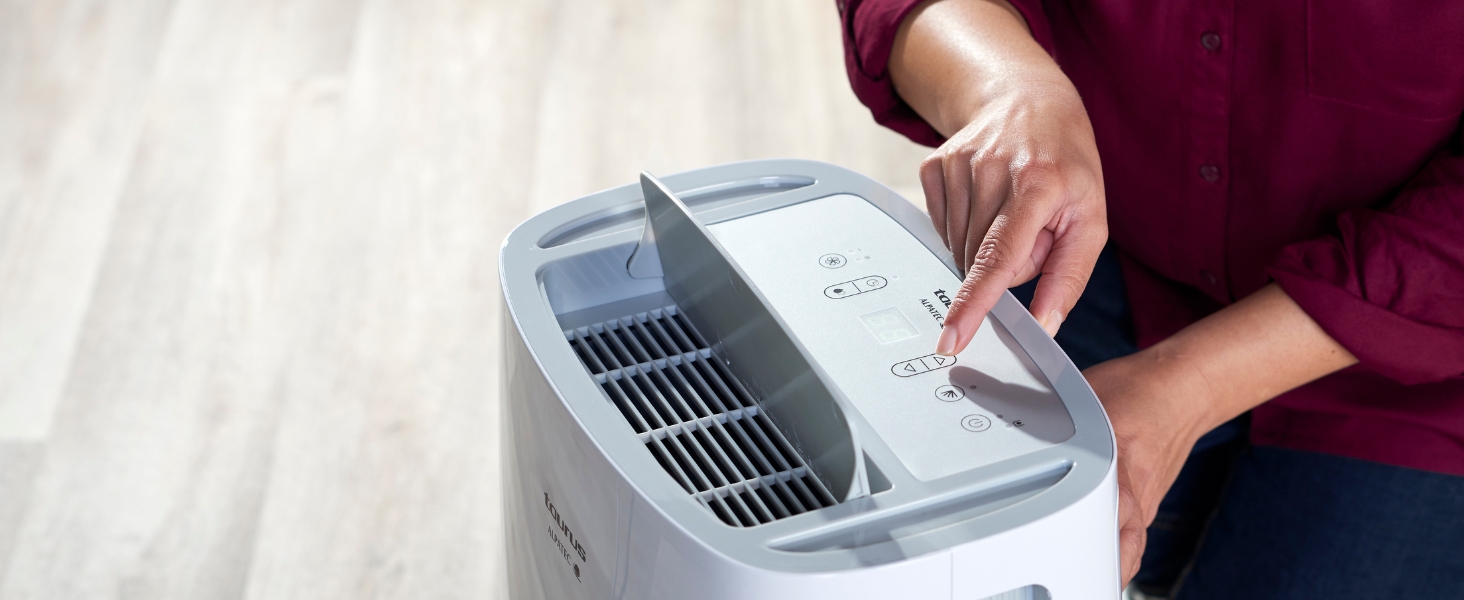 Le mani che azionano un dispositivo elettronico di colore chiaro con griglie di ventilazione visibili sembrano essere una sorta di manutenzione o configurazione dell'apparecchio.