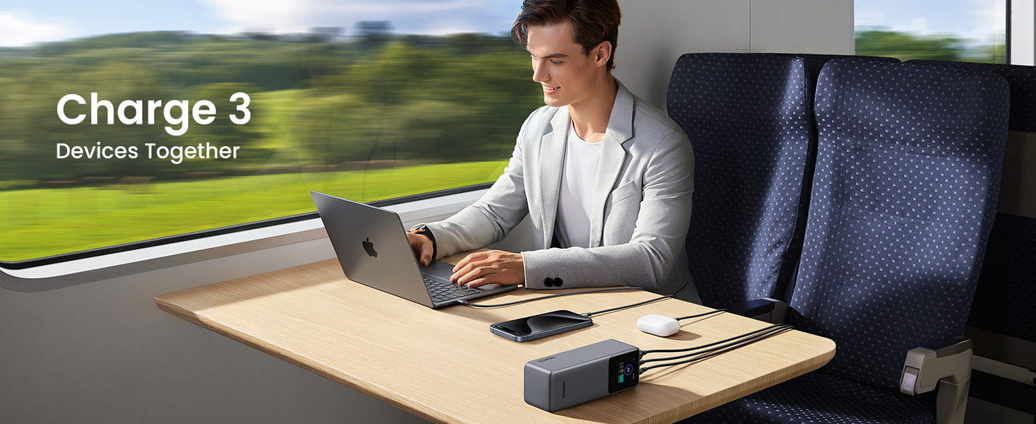 Man using UGREEN Nexode Power Bank 25000mAh 200W on train Charges 3 devices - laptop, cell phone and earbuds