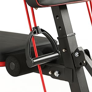 Close-up of an exercise equipment component, showing a black padded seat with red metal frame and an adjustable resistance handle or foot strap.