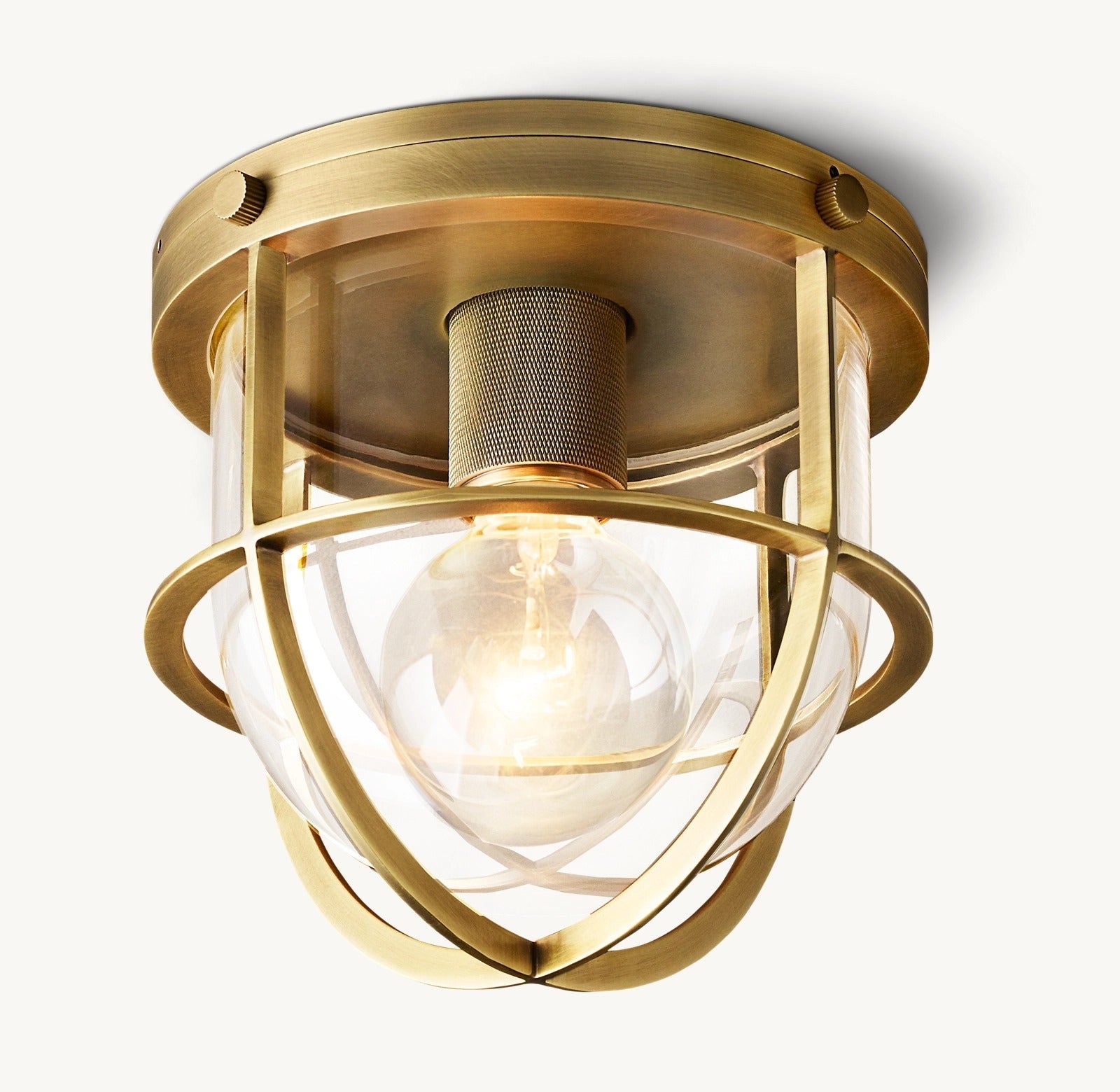 A brass-colored metal outdoor flushmount with a clear glass shade and a visible light bulb inside.