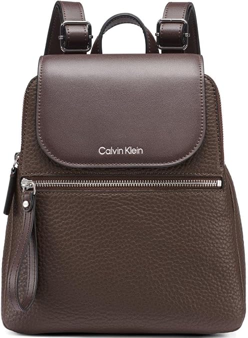 Calvin Klein dark brown backpack with flap closure, front zip pocket, and pebbled texture body. Features a smooth flap with silver 'Calvin Klein' logo, top carry handle, adjustable shoulder straps with buckles, and a zip pull wristlet strap.