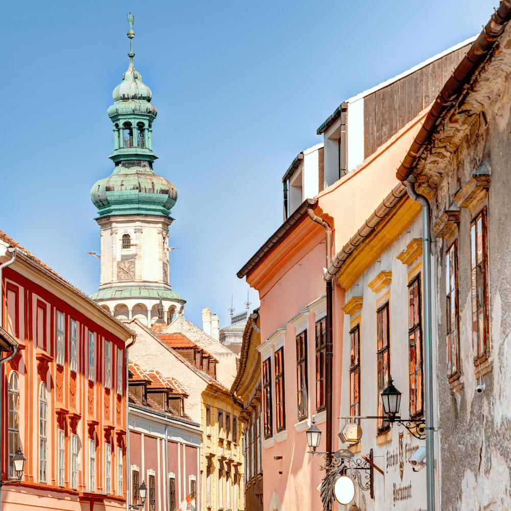 Hungary eSIM – baroque church tower and colorful old town street, travel eSIM for Hungary
