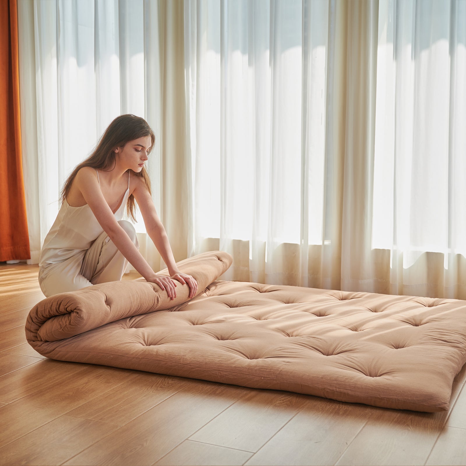 woman is folding a futon mattress.