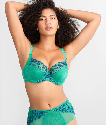 A model poses in a vibrant green lingerie set with lace detailing, showcasing a confident expression and curly hair.