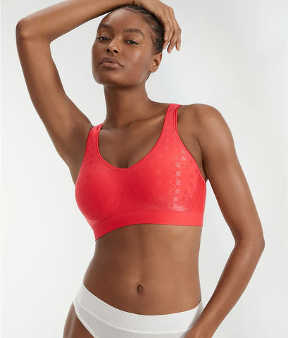 A model poses confidently in a red sports bra, showcasing a sleek design, paired with white underwear.