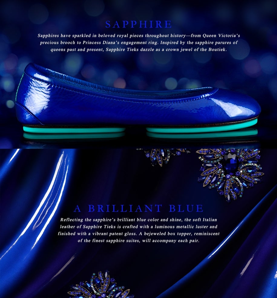 A Sapphire Tieks flat in glossy deep blue patent leather displayed against a rich blue satin background, accented by jeweled sapphire-inspired toppers, evoking regal elegance and timeless luxury.