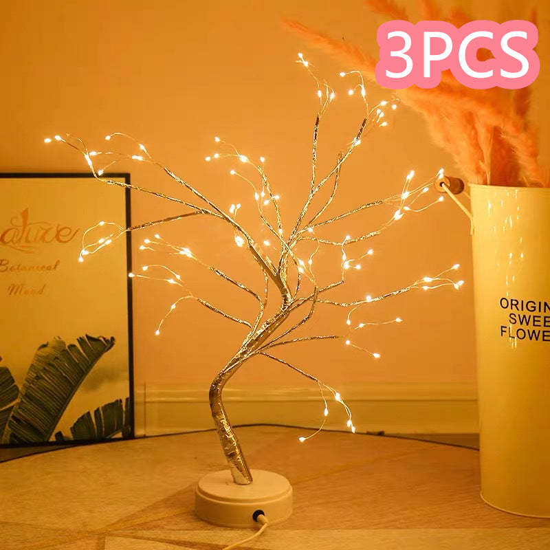 Decorative LED tree with lights on a wooden surface, next to a container labeled '3PCS'.