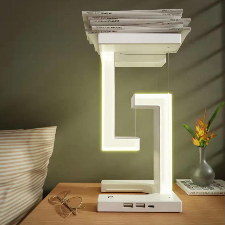 Modern LED table lamp on a wooden surface with books stacked on top, in a room setting.