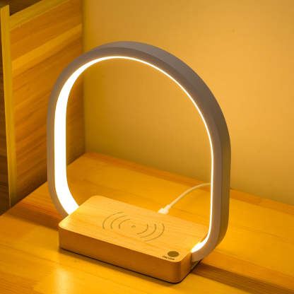 Modern lamp with wooden base and wireless charging pad on a wooden surface.