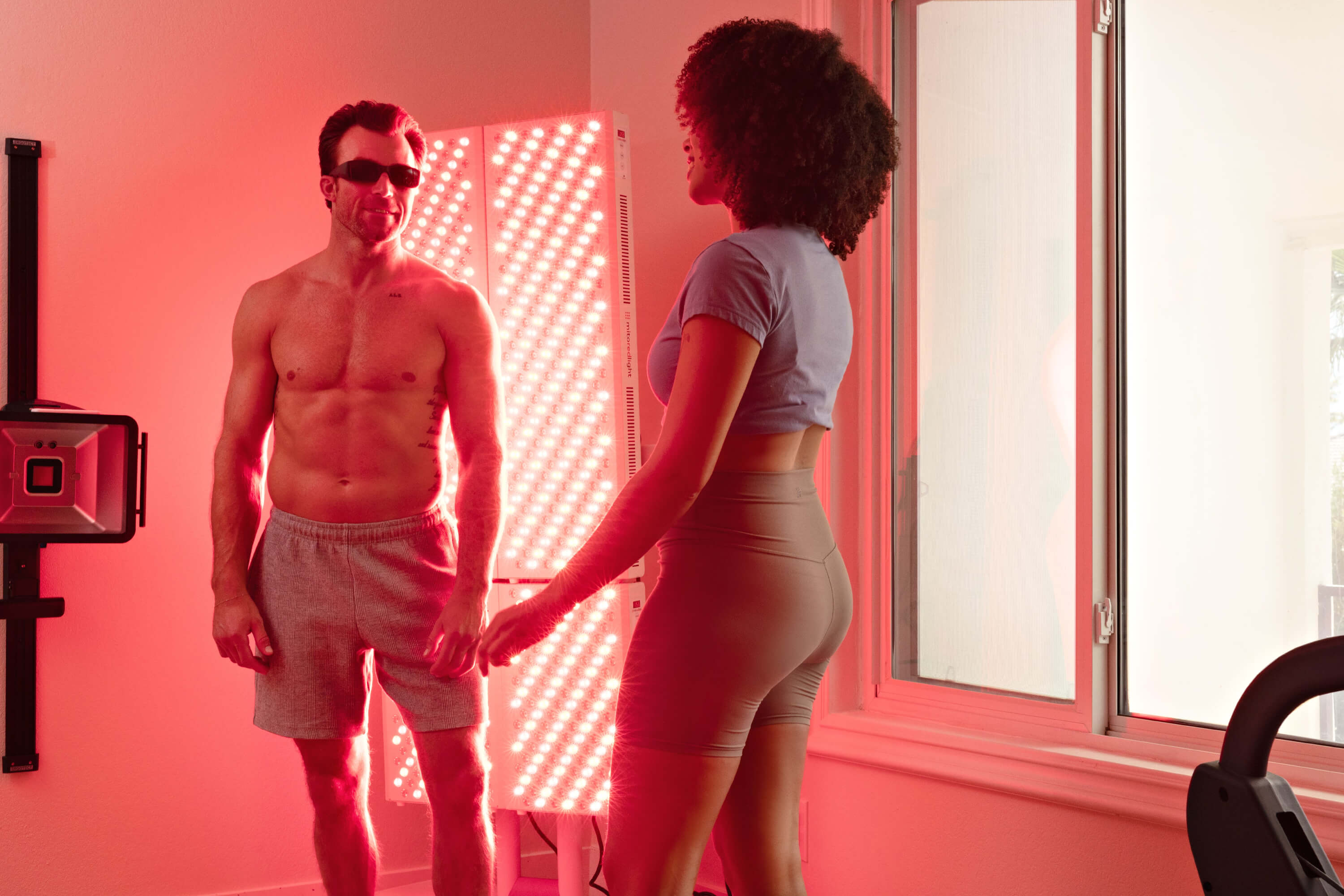 Man and woman standing in a room with red lighting and LED panels.
