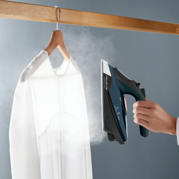 Using the cordless iron for vertical steaming on a hanging shirt, effortlessly smoothing wrinkles with powerful continuous steam