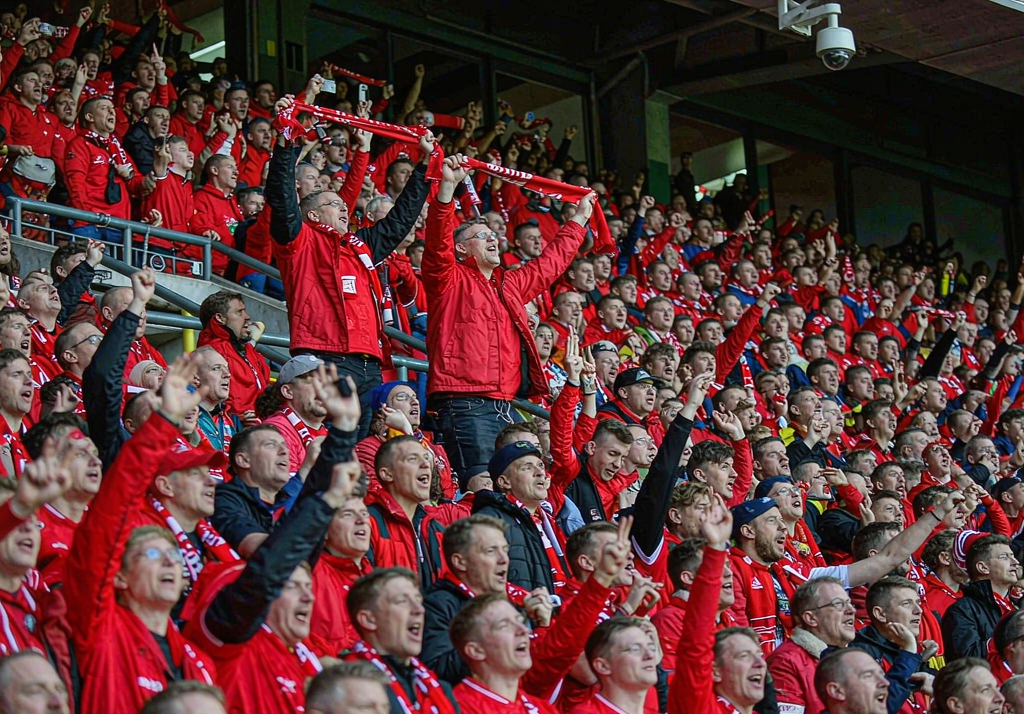 Liverpool fans at Anfield with red scarves and flags on the Kop