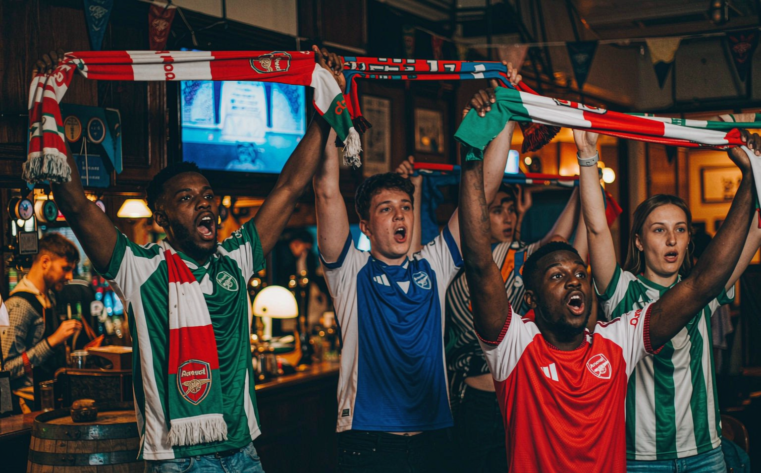 Fans in football shirts celebrating before a Premier League derby