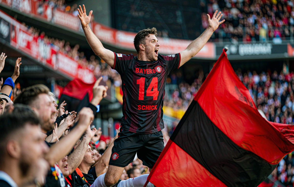 Bayer Leverkusen supporter celebrating in the crowd wearing the Schick 14 home shirt