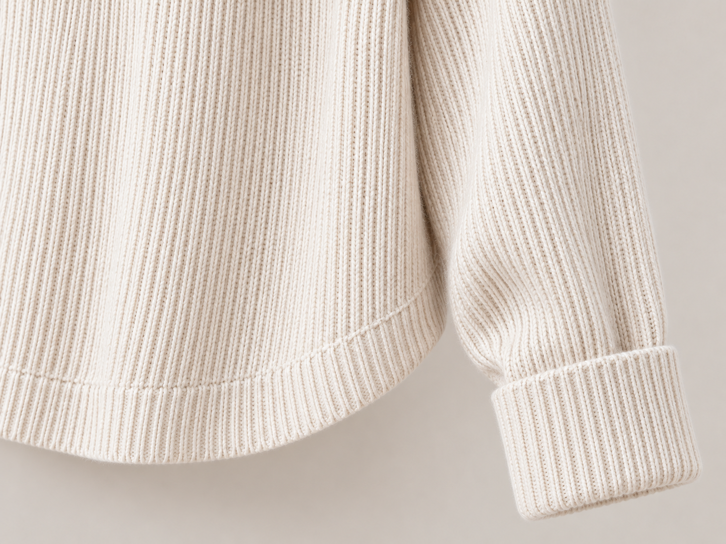 Close-up of the ribbed sleeve cuff and curved hem finish