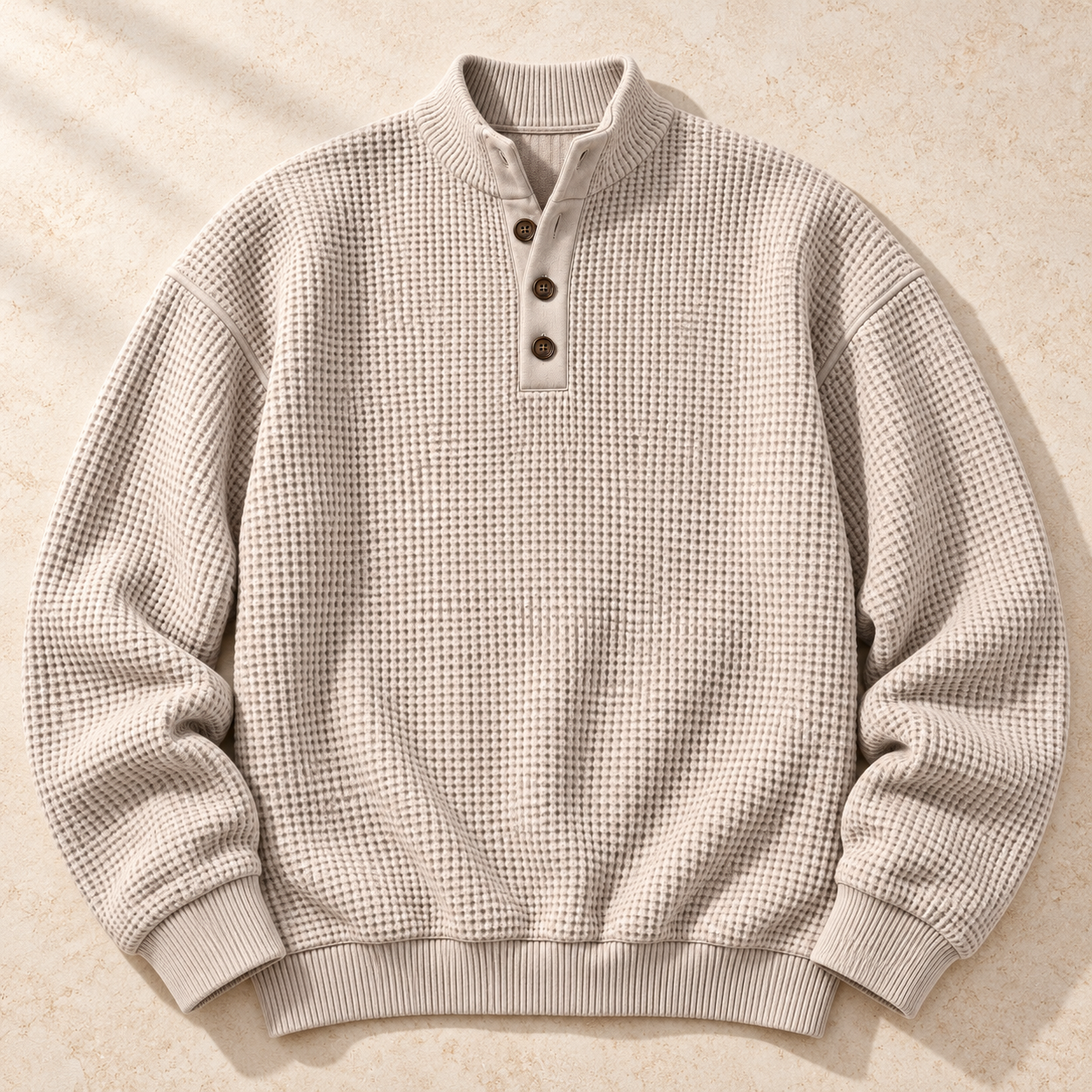 Beige mock-neck Henley sweater laid flat with three buttons, drop shoulders and ribbed cuffs and hem