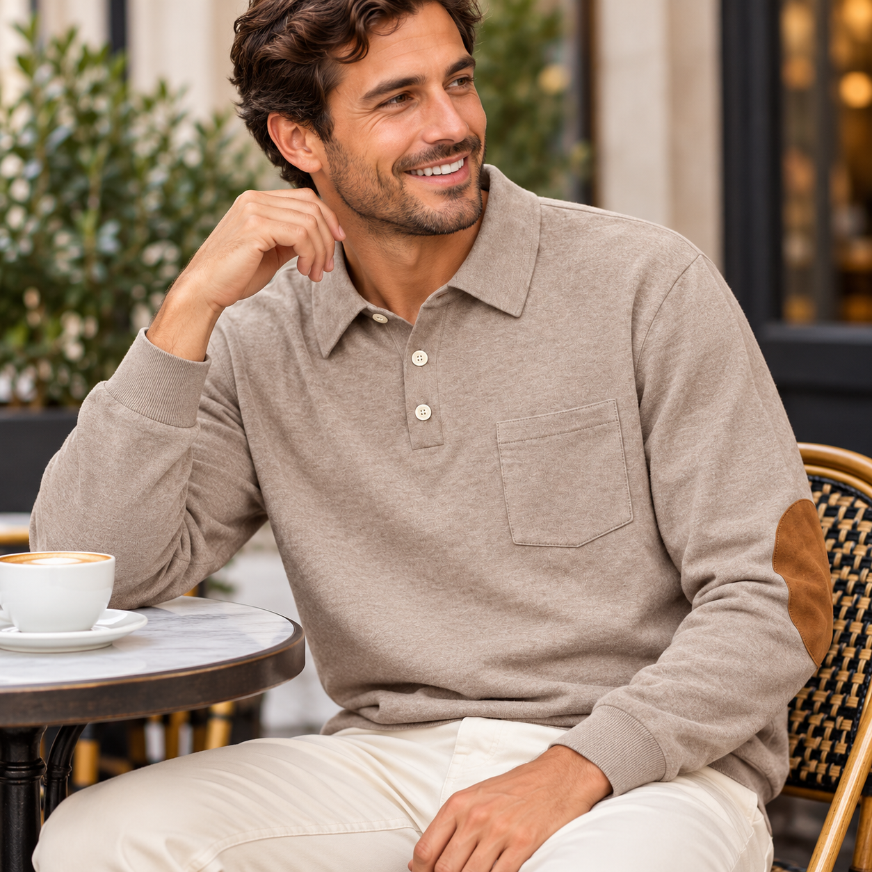 Man seated sideways at an outdoor café in Heather Khaki polo with one bent sleeve showing its brown elbow patch
