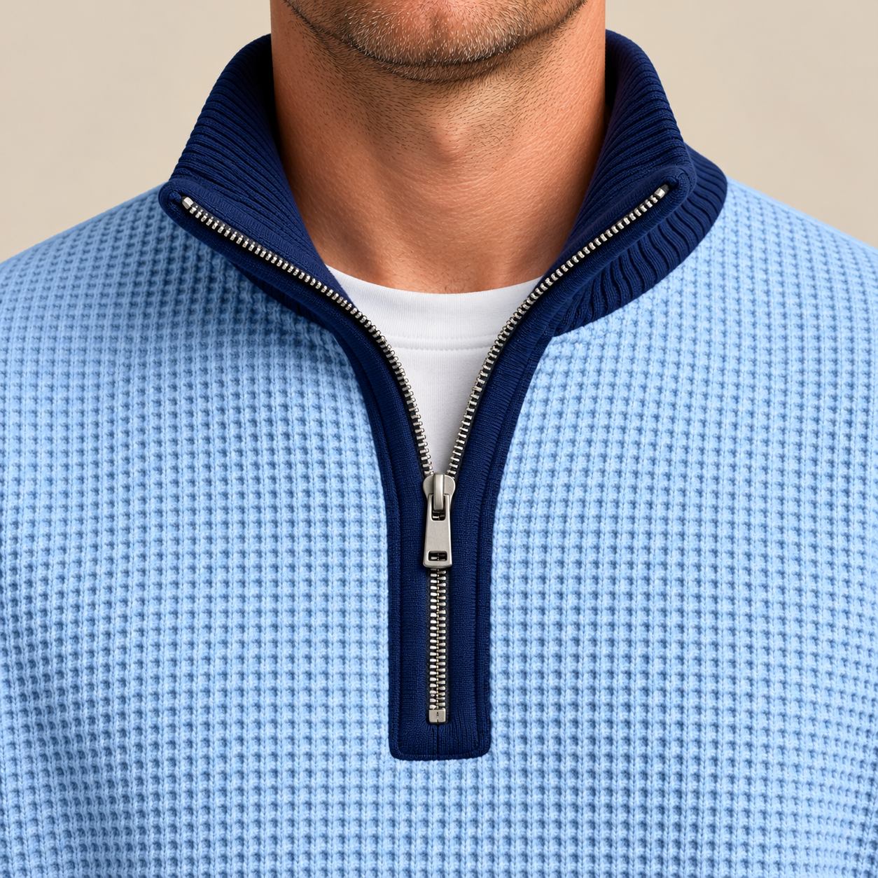 Close-up of a navy ribbed stand collar and silver short zipper on a light blue waffle-knit pullover