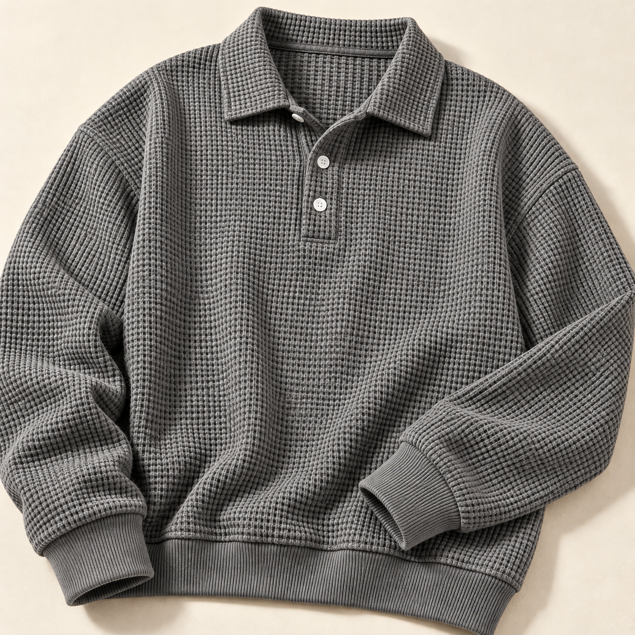 Gray waffle polo laid flat, showing waffle fabric, ribbed cuffs and hem