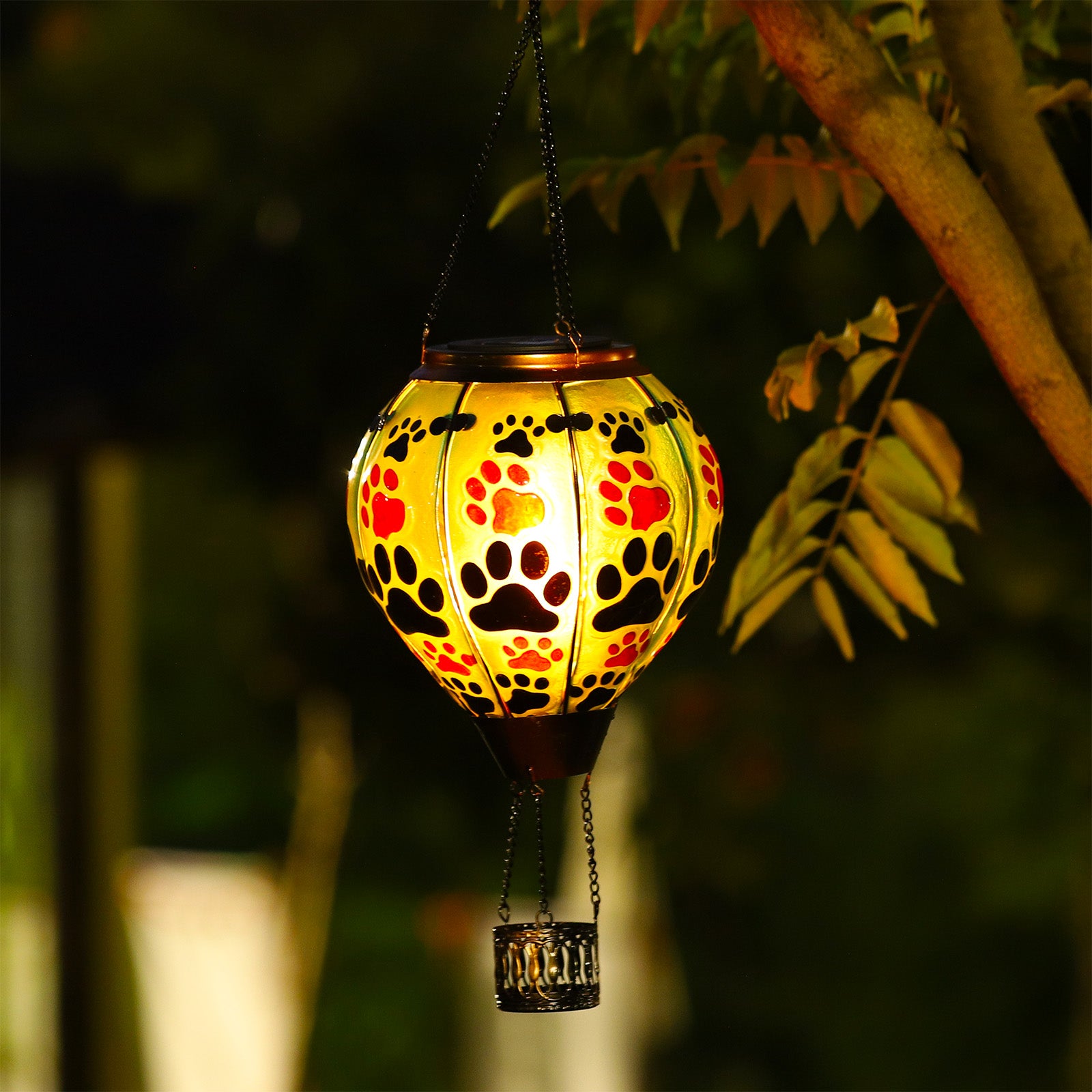 Cute paw print lantern suspended in garden, functioning as LED yard light and fun solar decoration for pet-friendly homes