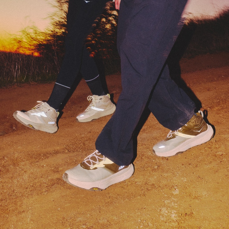 Two peoples reflective details on the Transport Hike glowing at dusk on a sandy path