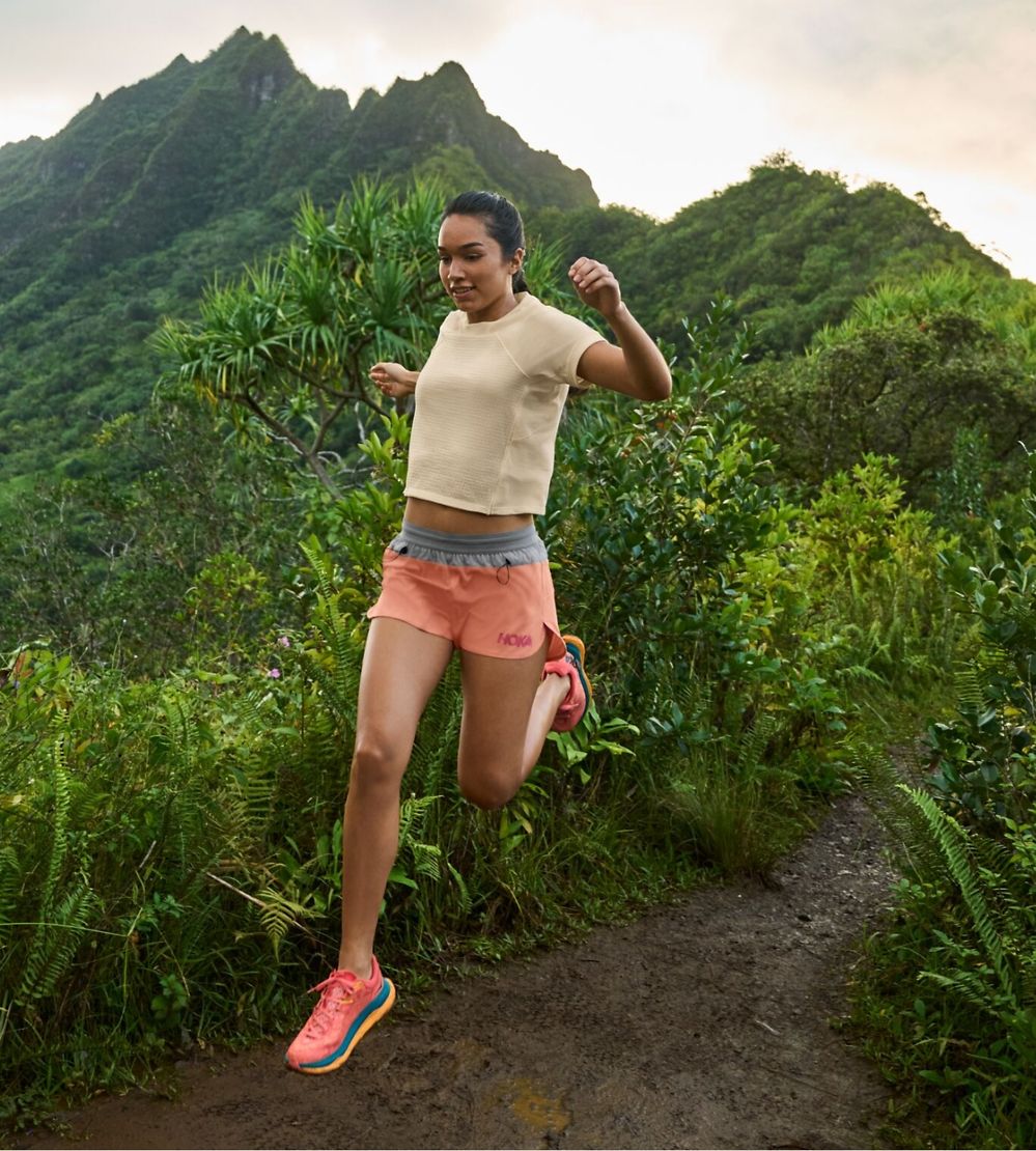 Woman running outside wearing HOKA shoes.