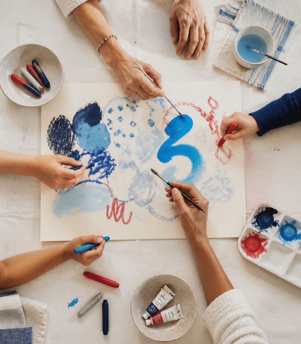 A group of children and adults making a shared colorful artwork