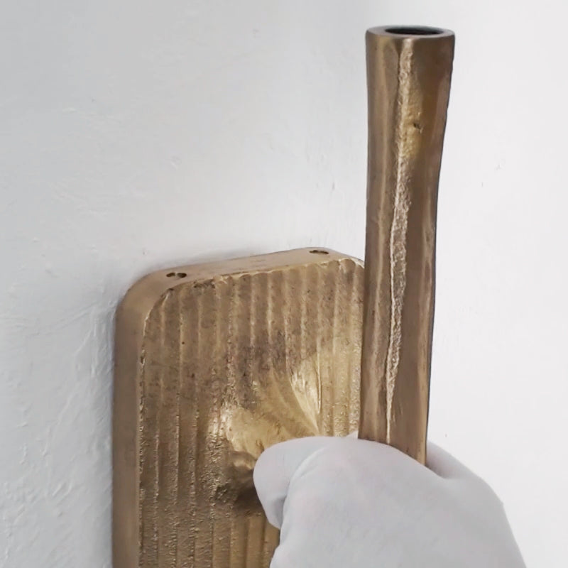 Hand holding the hammered brass backplate and torch stem hardware
