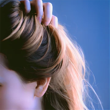 Close-up of ombre hair transitioning from dark brown to blonde against a blue background.