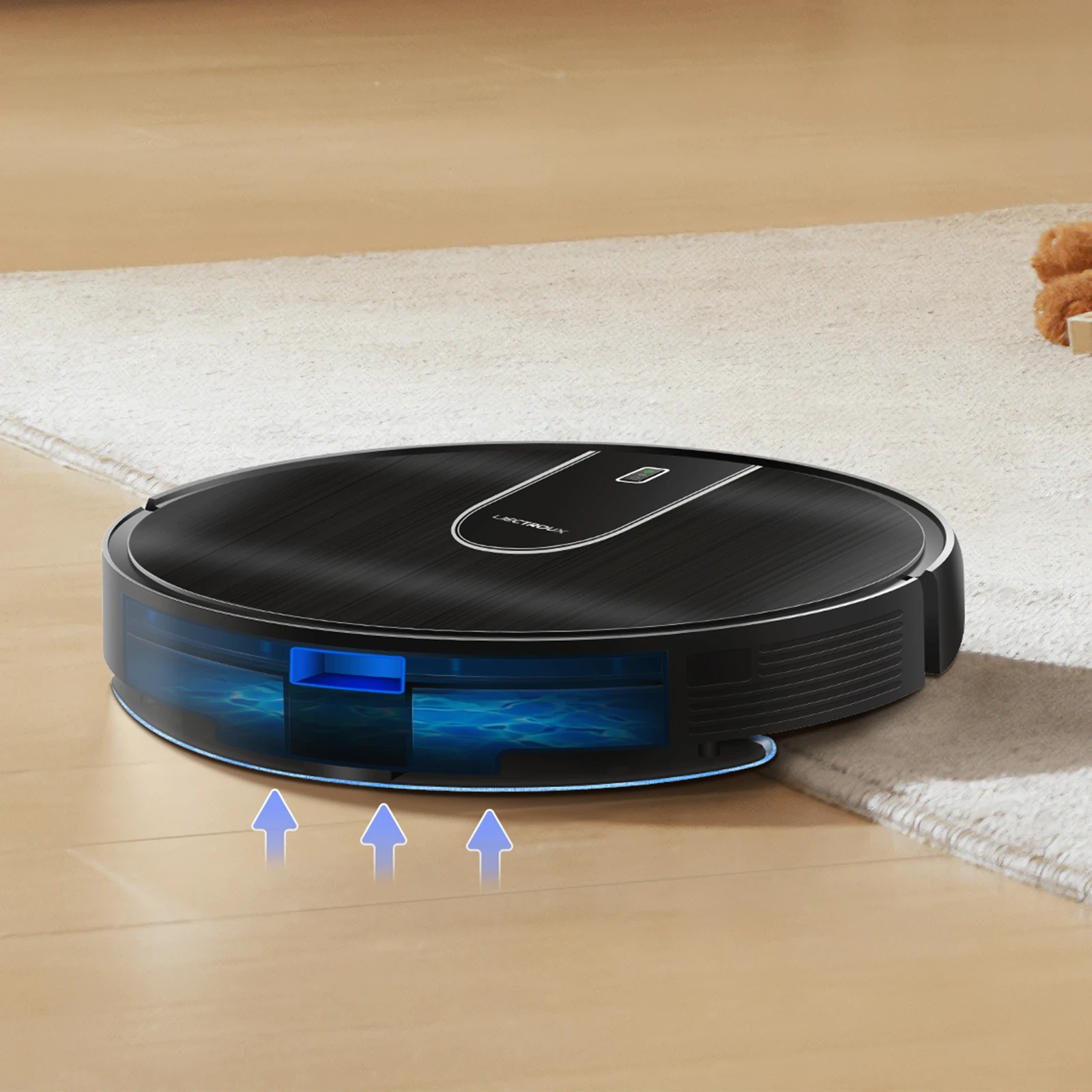 Black robot vacuum cleaner with blue LED accents and transparent water tank on hardwood floor transitioning to white rug.
