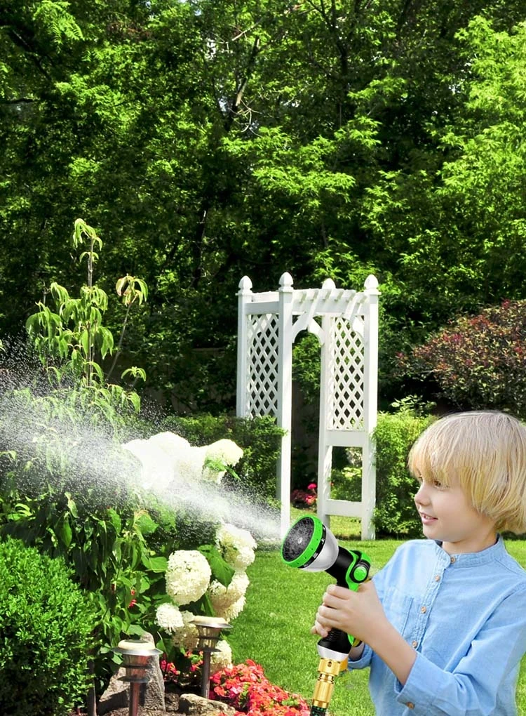 Black and green multi-pattern garden hose nozzle spraying water on garden plants.