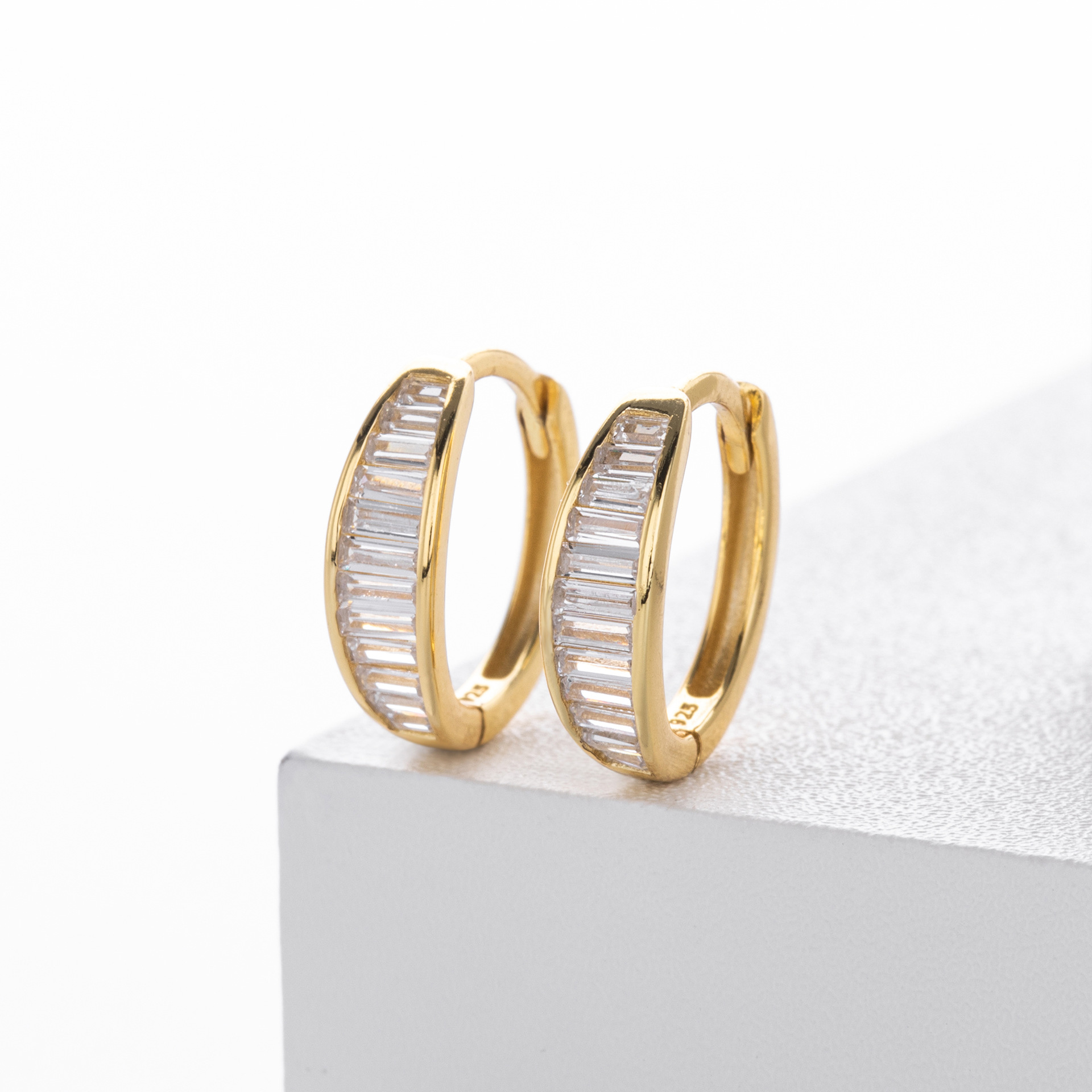 These sophisticated gold hoop earrings feature a sleek design with baguette
