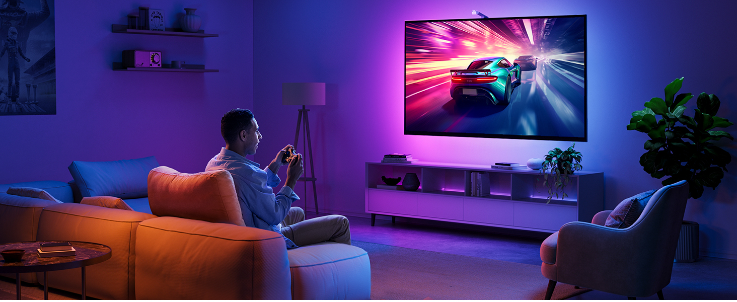 a man sitting in a chair in a living room playing a video game on a smart tv.