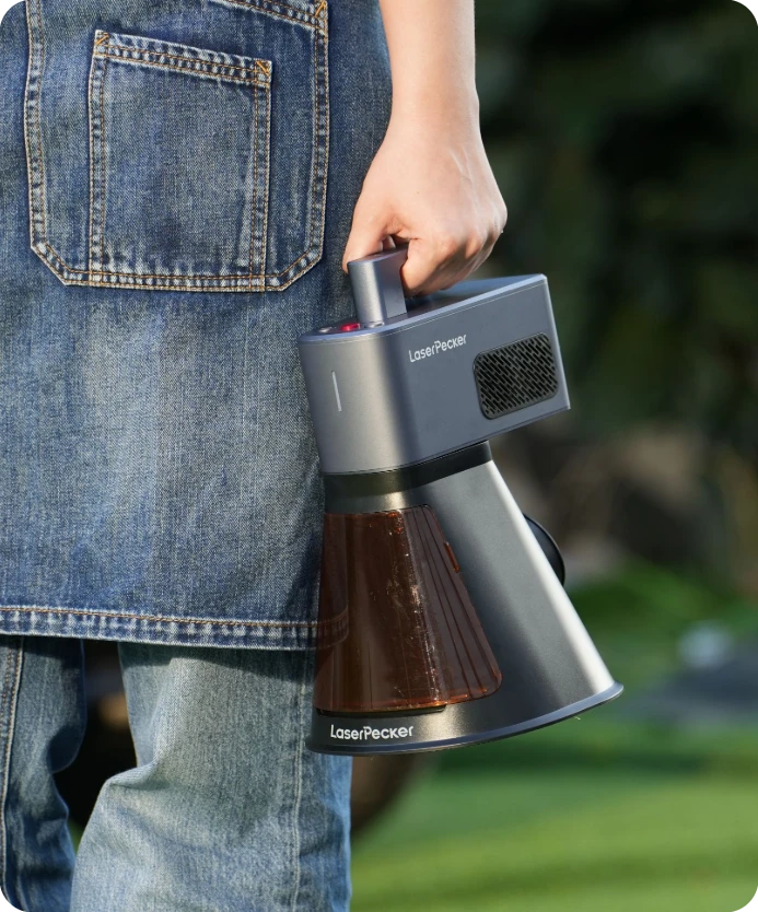 A person carrying the compact LaserPecker LP2 Plus laser engraver by its handle, demonstrating its lightweight and portable design for on-the-go crafting.