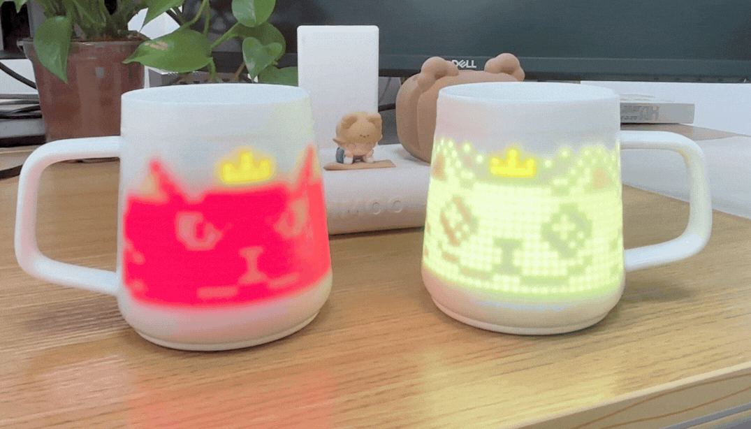 Pixel Mug displaying animated Crowned Kitten pixel art on a desk