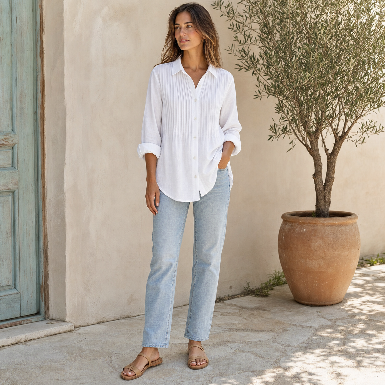 Woman wearing the white pleated cotton-linen shirt in a sunlit courtyard