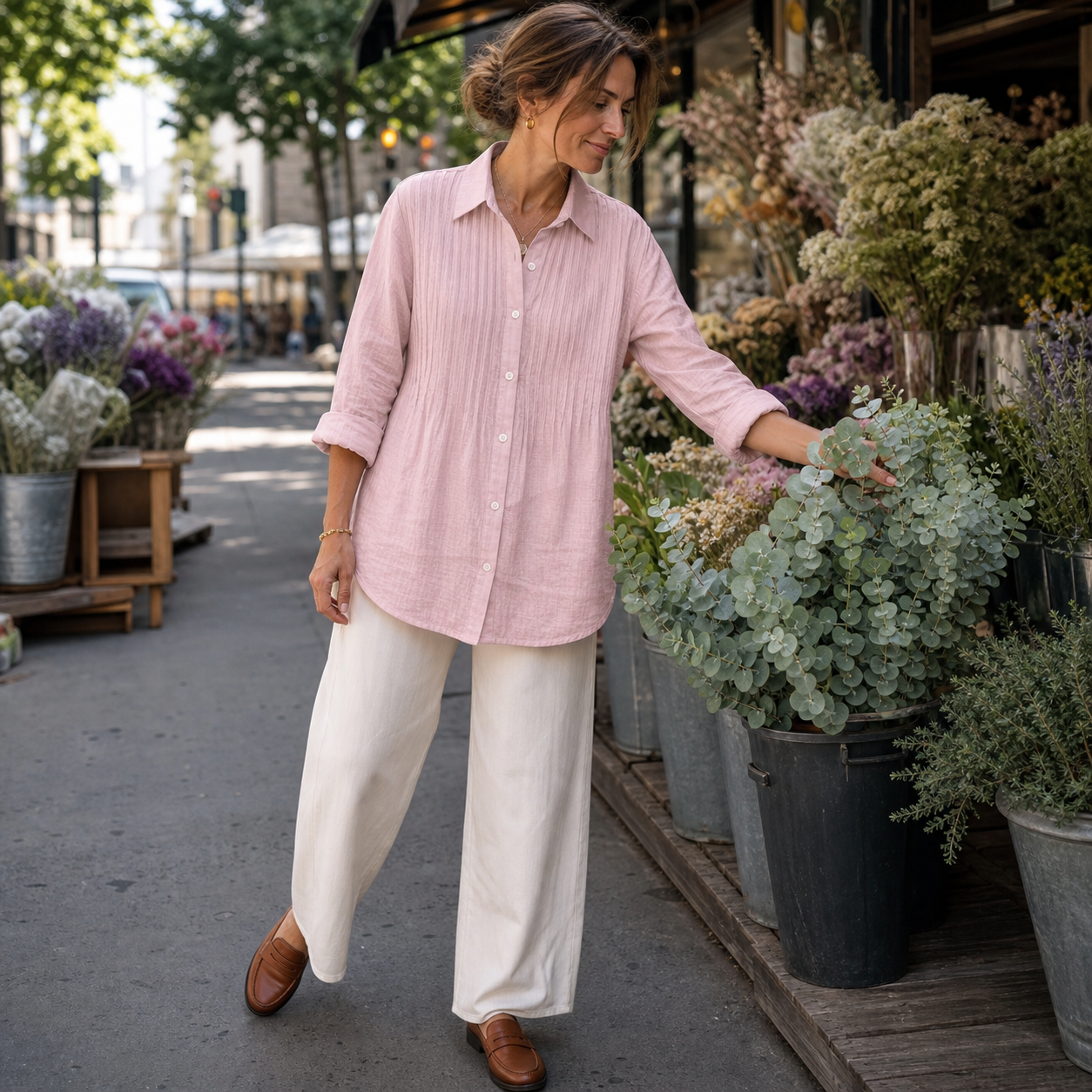 Woman wearing the pale pink pleated shirt while choosing eucalyptus at a flower market