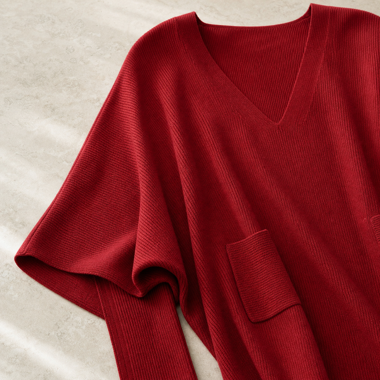 Close-up of ribbed red knit V-neck and pocket detail