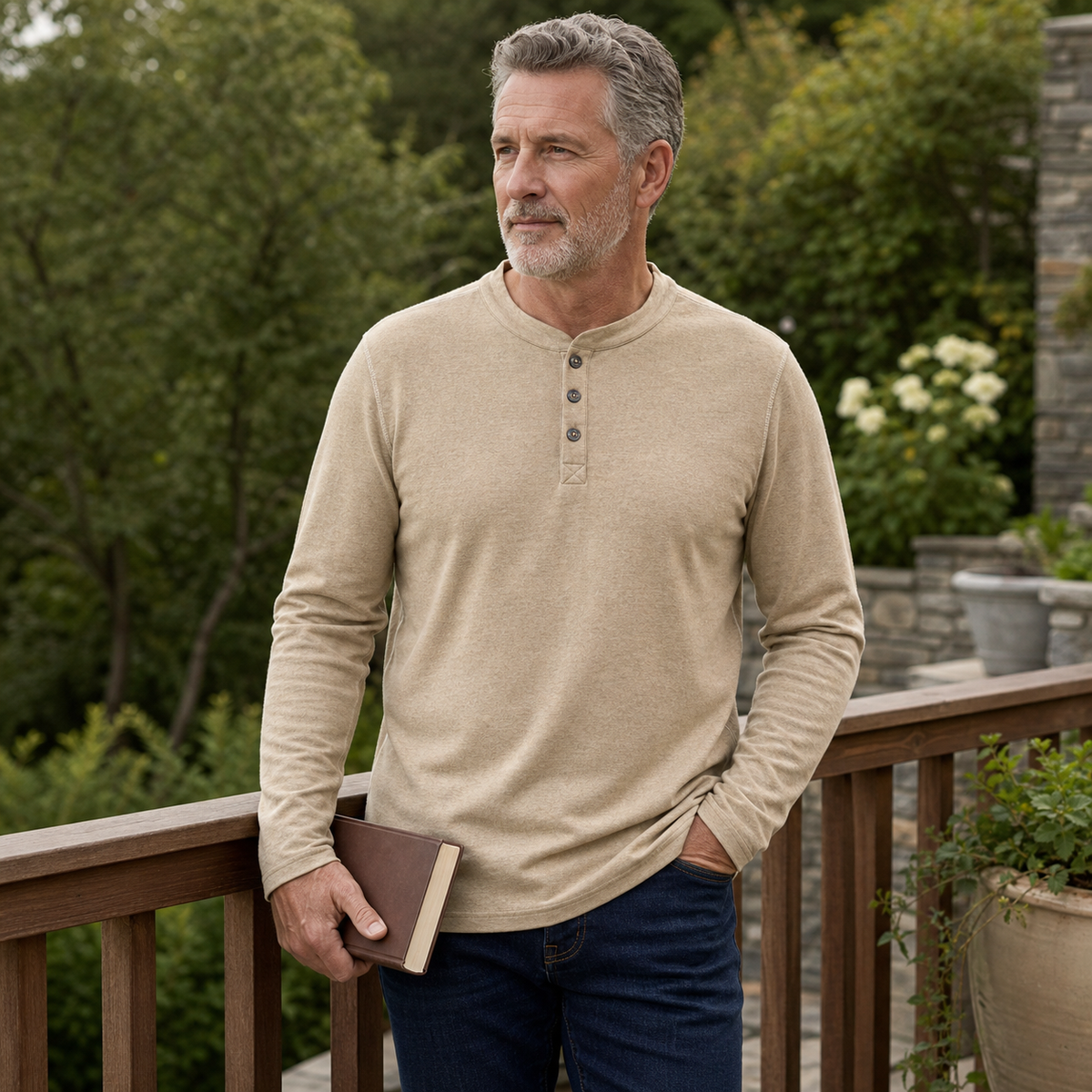 Reifer Mann im beigefarbenen Henley-Shirt auf der Terrasse