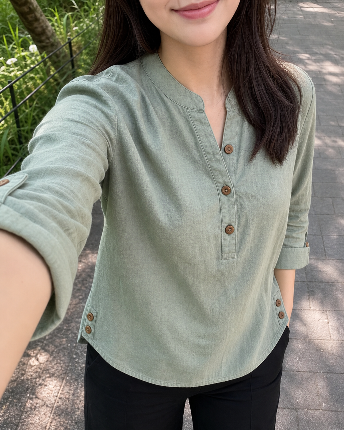 Woman styling the band-collar blouse in sage green
