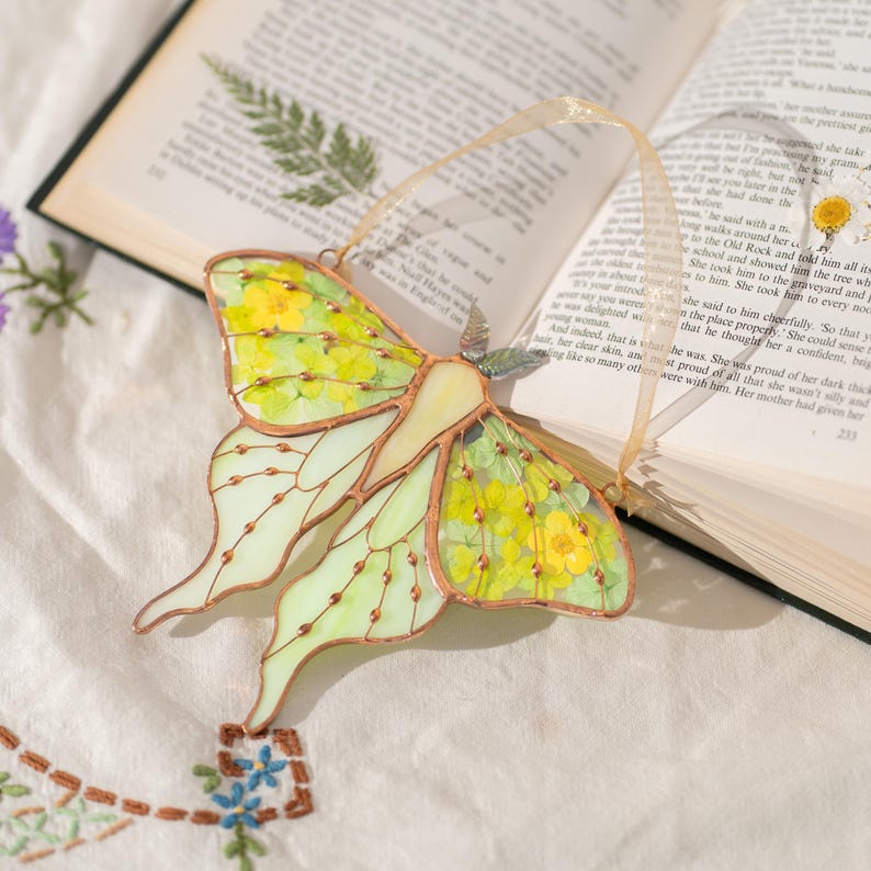 Apanhador de sol de vitral em forma de mariposa com flor prensada para janela, decoração que captura a luz.